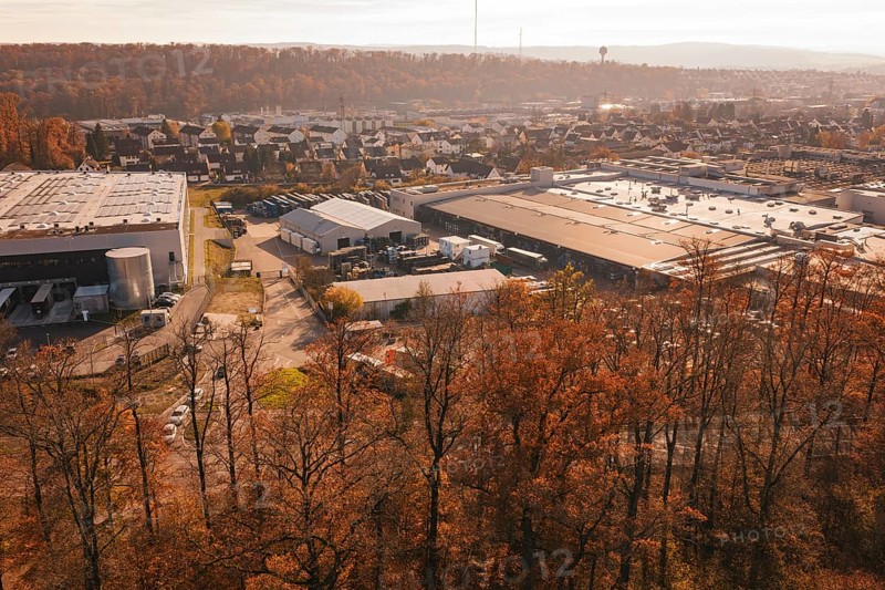 Industrial plant on the outskirts of town, surrounded by autumnal forest and light haze, MÃ¼hlacker, Enzkreis, Germany