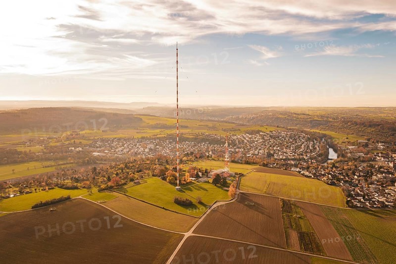 A radio tower stands in the middle of a vast, autumnal landscape next to a village, MÃ¼hlacker, Enzkreis, Germany