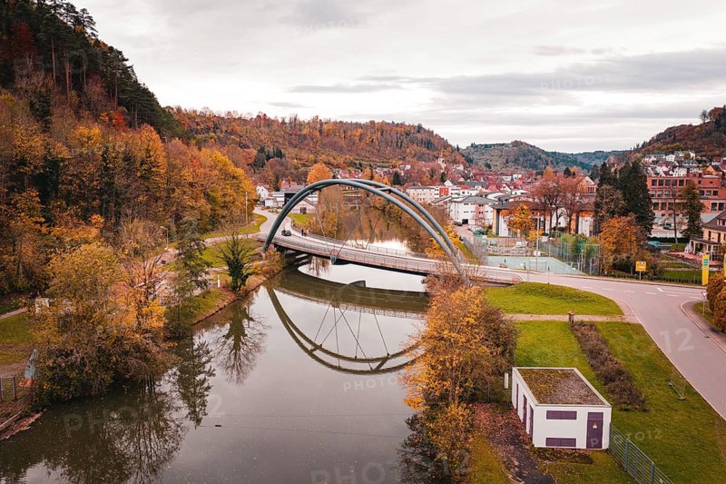 Beautiful bridge in autumn landscape, framed by colorful trees and reflected in water, Sulz am Neckar, Germany