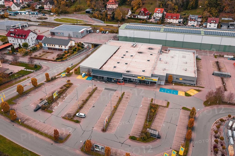 Large supermarket with adjacent parking lot and surrounding residential buildings in an autumn city scene, Sulz am Neckar, Germany
