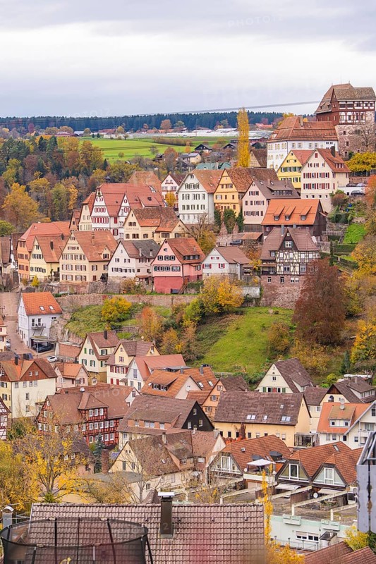 Idyllic city view with half-timbered houses on a hill surrounded by autumn leaves and cloudy sky, Altensteig, Calw district, Germany