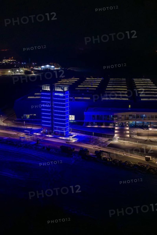Night view of a factory with a blue illuminated tower in dark surroundings, Nagold, Calw district, Germany