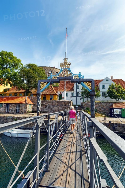 Female walker on bridge for pedestrians between ChristiansÃ¸ and FrederiksÃ¸, Christiansö and Frederiksö, Ertholmene, Pea Islands, Bornholm, Denmark