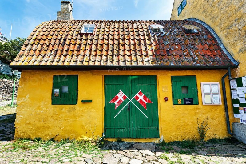 ChristiansÃ¸ Skole, smallest school in Denmark, curved tile roof, characteristic yellow and green, crossed Danish flags, Dannebrog, ChristiansÃ¸, Christiansö, Ertholmene, Pea Islands, Bornholm, Denmark