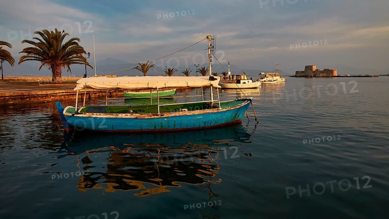 Port of Nauplion, Bourtzi island fortress, A blue boat in the harbor with palm trees and view of a castle in the evening light, Nauplion, Nafplio, Peloponnese, Greece