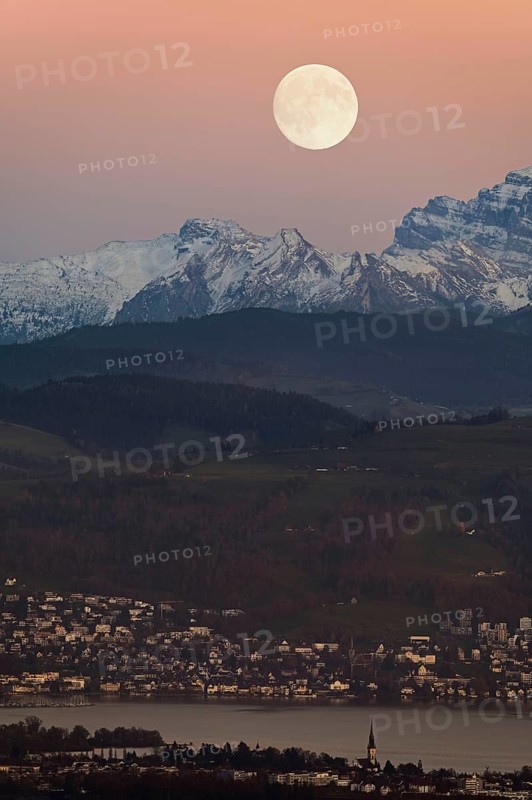 View from Horben of Lake Zug with the town of Cham and Zug, behind it the snow-capped mountains FlÃ¼brig and VrenelisgÃ¤rtli, in the light of a full moon, Beinwil-Freiamt, Canton, Aargau, Switzerland