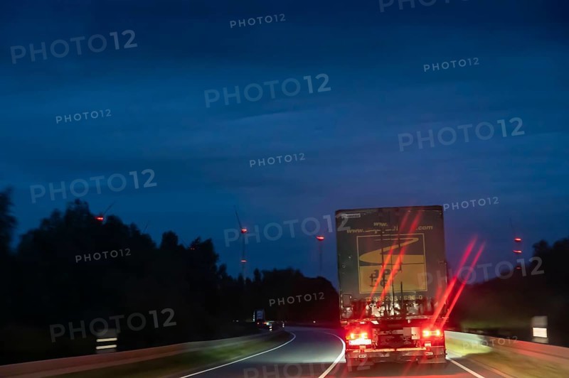 Truck on federal highway at night, wind turbine lights on the left, Schleswig-Holstein, Germany