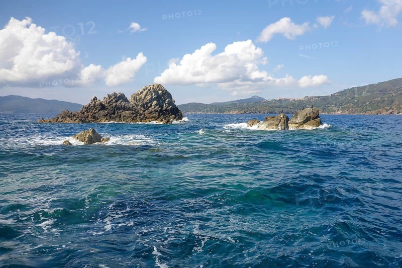Rock reef with three rocks rising out of the sea Water above water surface Sea level off the coast of the Tuscan island of Elba in the Mediterranean, Elba, Tuscany, Italy