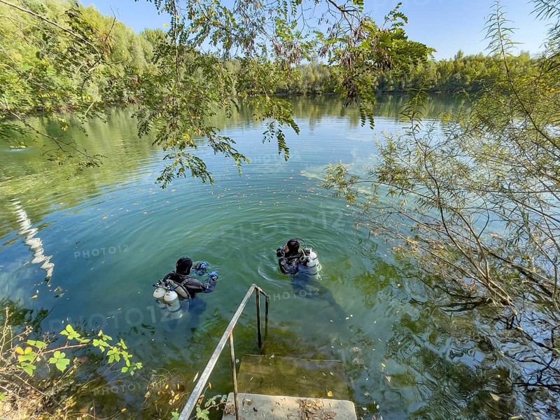 Recreational divers with diving equipment Diving tanks swim near the shore on the water surface of a small lake, Germany