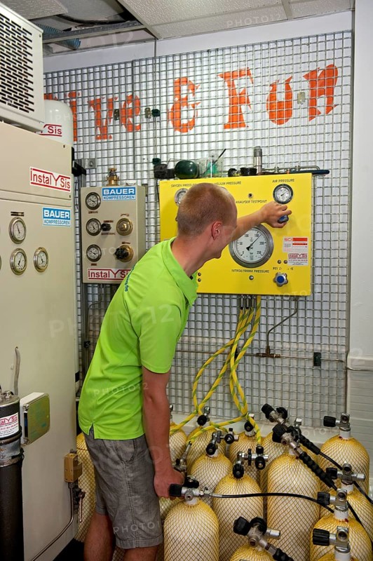 Dive instructor operates compressor fills scuba tanks scuba diving equipment for recreational divers for scuba diving with compressed air, international
