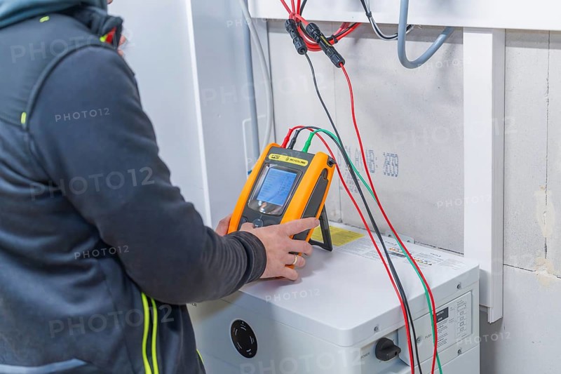 Technician checks solar system with measuring device device and cables in the device