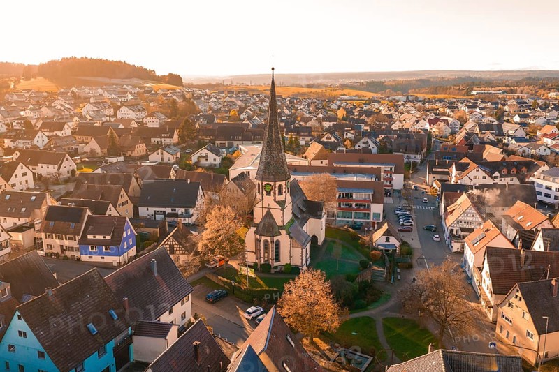Aerial view of a village with church and autumn trees in soft sunset light, Althengstett, Calw district, Germany