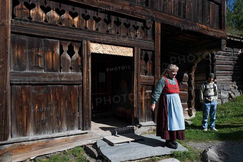 Tourist guide in traditional traditional costume and visitor, BjÃ¸rnstad, farm from VÃ¥gÃ¥, Maihaugen open-air museum with houses and objects from farms in Gudbrandsdal, Lillehammer am MjÃ¸sa Lake, Fylke Innlandet Municipality, Norway