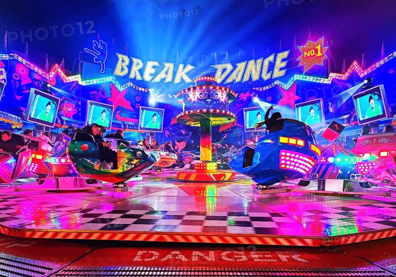 People in the colorful illuminated break dance ride at night at the All Saints Fair, Soest, North Rhine-Westphalia, Germany
