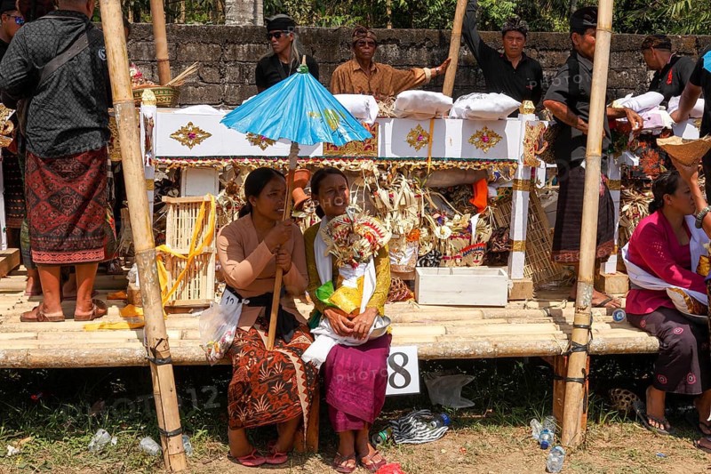 Festively dressed woman and men at a cremation ceremony (Ngaben), Ubud, Bali, Indonesia