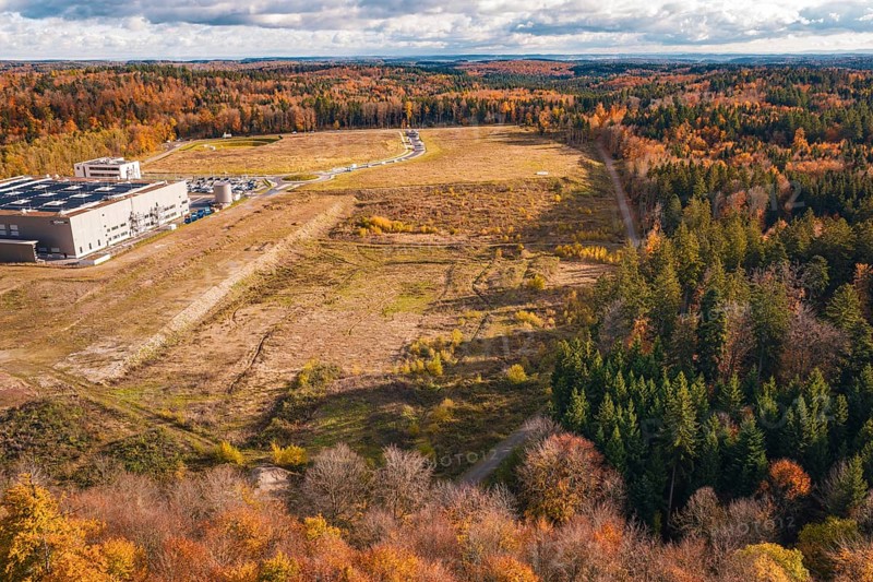 Industrial plant in autumn, surrounded by diverse forest in an open landscape, new Lindenrain industrial park, Calw, Black Forest, Germany