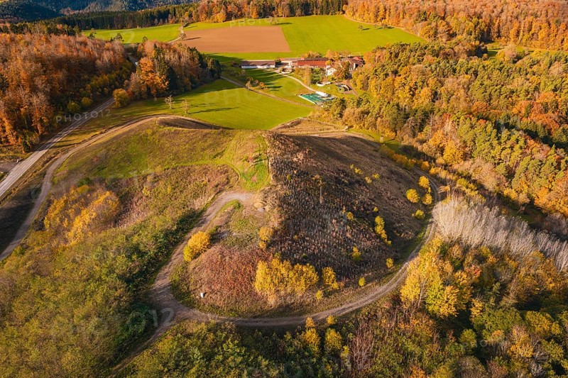 Hilly autumn landscape with colorful trees and fields, farm and winding paths, new Lindenrain industrial park, Calw, Black Forest, Germany
