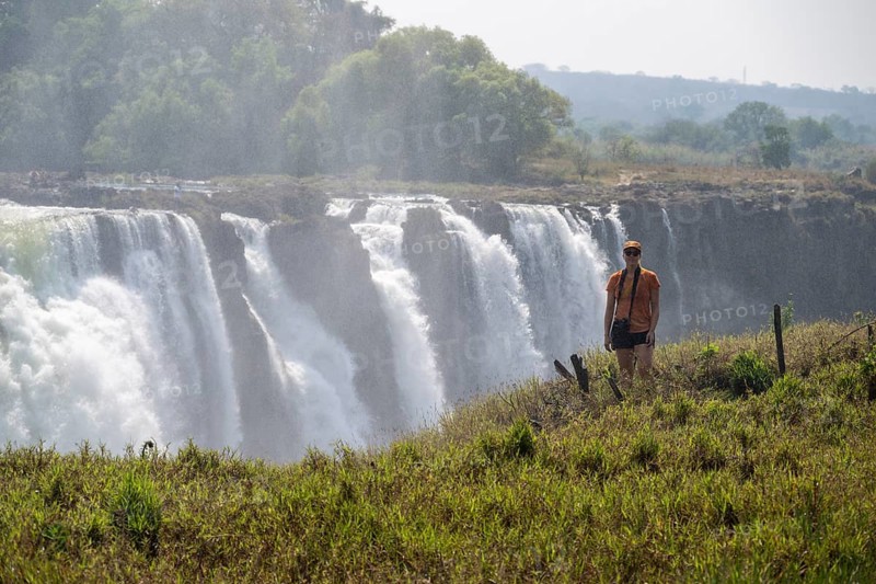 Tourist looking at waterfalls, water plunging into the depths, Victoria Falls, Zimbabwe