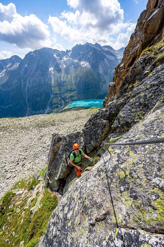 Mountaineer climbs on steep rock face in the secured via ferrata Crocodile Mountain Lake at Bergseeschijen-Vorbau, Göscheneralp, Canton of Uri, Switzerland