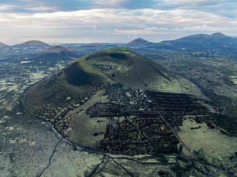 MontaÃ±a Negra volcano, picturesque volcanic landscape with volcanic crater at sunrise, Parque Natural de Los Volcanes, aerial view, Lanzarote, Canary Islands, Spain