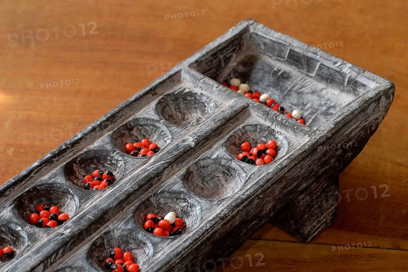 Traditional wooden game Pallankujhi, Pallamkuzhi, Pallangulli, Pallankulli or Alagulimane with red and black beans, Chettinad, Tamil Nadu, India