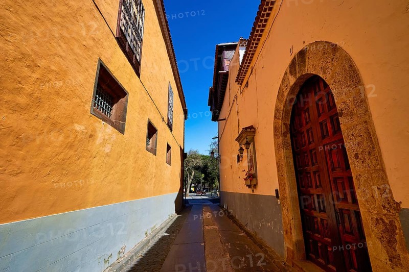 Narrow historic alley with yellow facades and wooden doors in the shade of a wall, UNESCO World Heritage Old Town of San Crstobal de La Laguna, La Laguna, Tenerife, Canary Islands, Spain