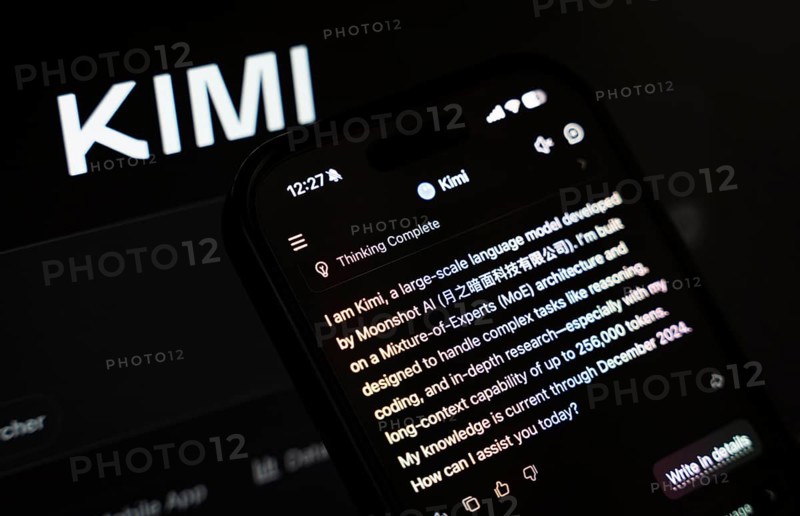 In this photo illustration, a person uses the Kimi AI chatbot on a smartphone while the KIMI logo is displayed on a screen in the background, in New Delhi, India on 20 November 2025. Kimi AI is a Chinese artificial intelligence chatbot and assistant developed by Moonshot AI, a fast-growing tech company in China