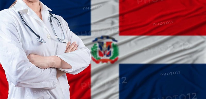 Doctor with crossed arms on Dominican Republic flag. Dominican health and care concept. Female doctor on Dominican Republic flag