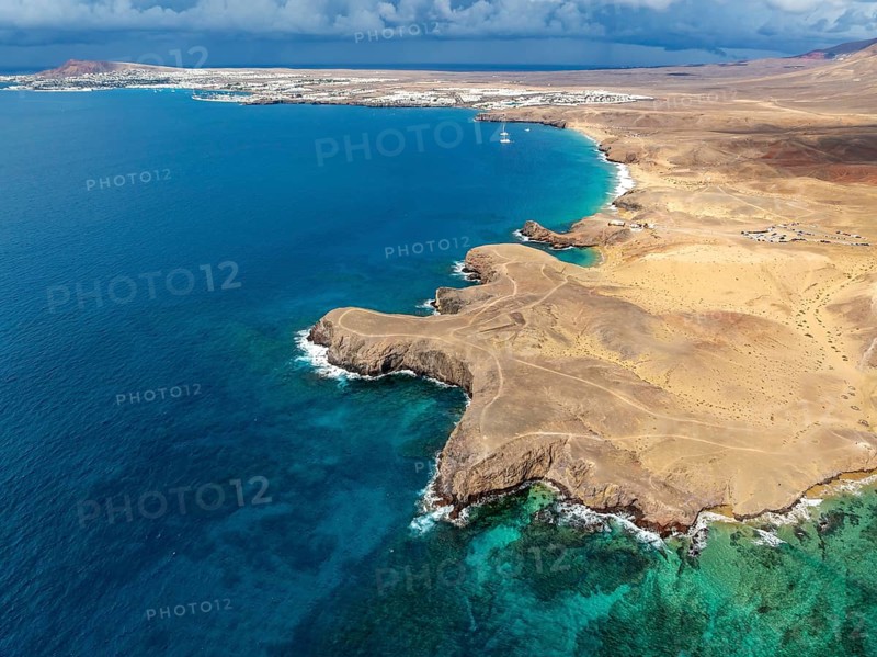 Coast with Playa de Papagayo beach and blue sea, arid landscape of Los Ajaches Natural Park, aerial view, Lanzarote, Canary Islands, Spain
