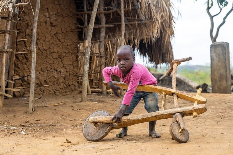 Child playing with a self-made wooden balance bike, in a Sadaani village, Tanga, Tanzania