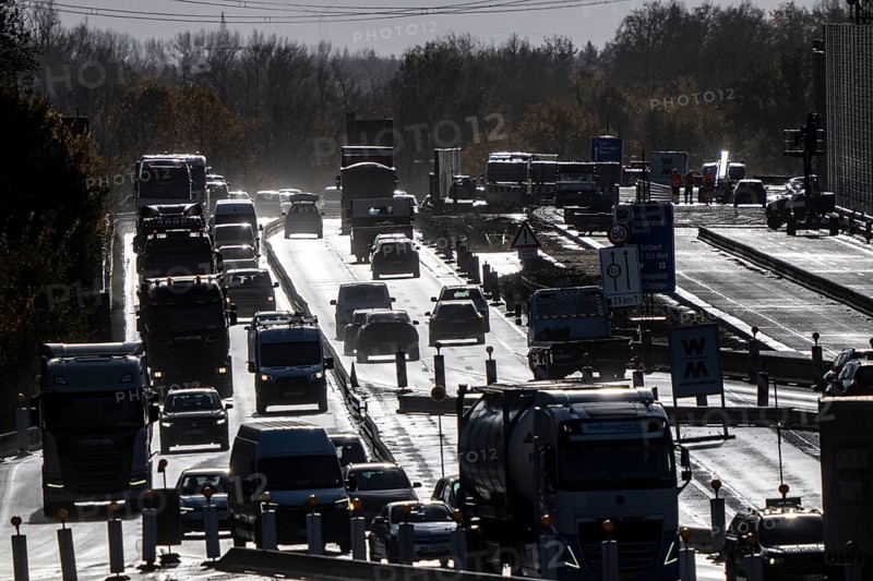Highway construction site, the A57 is extended to 6 lanes on the section between the Meerbusch motorway junction and the Oppum junction, traffic runs parallel to 2 narrowed lanes, wet road after rain shower, Krefeld, North Rhine-Westphalia, Germany