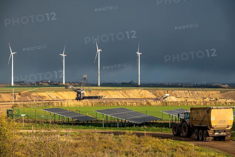 Parts of an 86.5 MW peak open-air photovoltaic system, from RWE, with over 141, 000 solar modules, on a side strip, along the A44 motorway near JÃ¼chen, on the timber triangle, recultivated open-cast mining site, in the background RWE settling in the open-cast mine, fill the pit with debris from the Garzweiler open-cast mine, JÃ¼chen wind farm, North Rhine-Westphalia, Germany