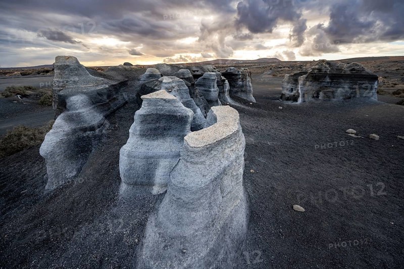 Eroded rock formations, volcanic landscape with dramatic cloudy sky at sunset, Ciudad Estratificada or Los Roferos, Antigua Rofera de Teseguite, Lanzarote, Canary Islands, Spain