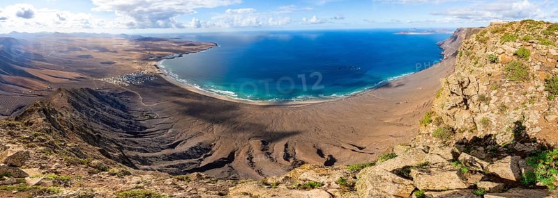 Panorama at Castillejo viewpoint, view from the Risco de Famara cliffs to the coast and the sea with Famara beach, Playa de Famara with La Calaeta, Lanzarote, Canary Islands, Spain