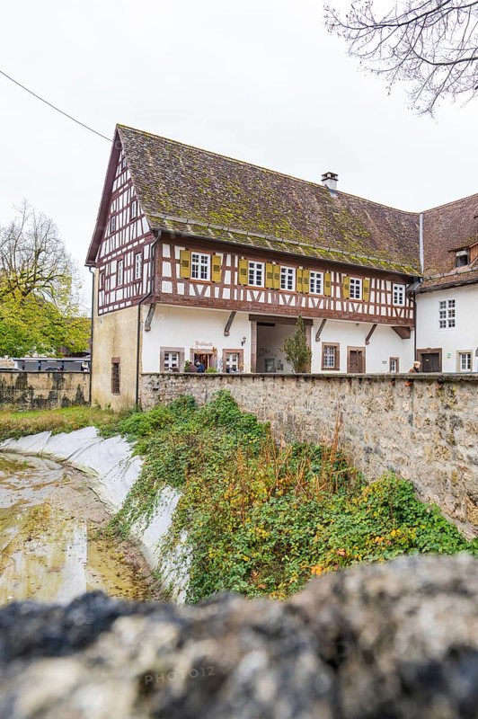 Well-preserved traditional half-timbered house next to a stone wall in a rural area, Wasserschloss Glatt, Sulz, Germany