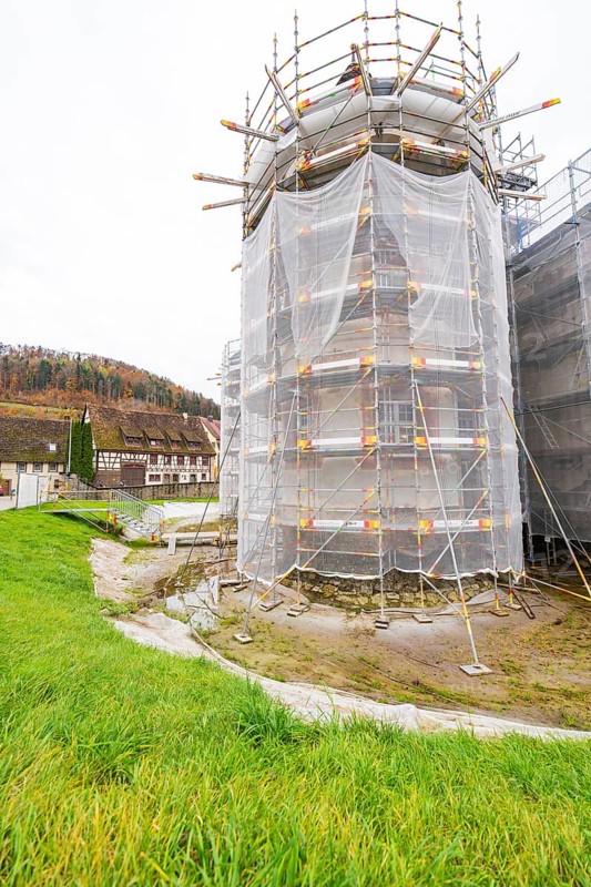 Large tower in scaffolding with surrounding meadow, trees and buildings in the background, Wasserschloss Glatt, Sulz, Germany