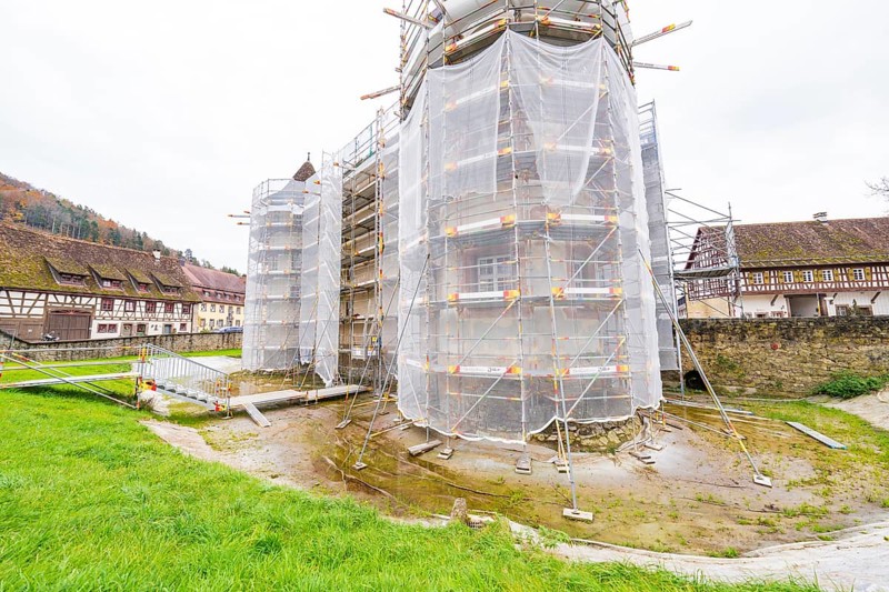 A rural-style renovated building with scaffolding and tarpaulins, surrounded by green spaces, Wasserschloss Glatt, Sulz, Germany
