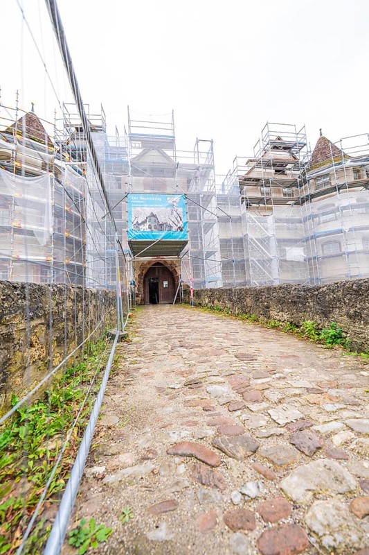 Paved path leads to a scaffolded entrance gate of a converted medieval building, Wasserschloss Glatt, Sulz, Germany