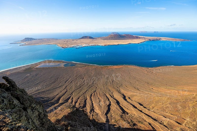 View of steep cliffs by the sea and island of La Graciosa with volcanic craters in the evening light, Mirador del RÃ­o viewpoint designed by artist CÃ©sar Manrique, Lanzarote, Canary Islands, Spain