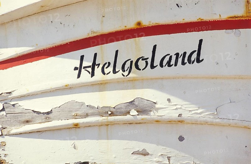 Weathered Heligoland lettering on white boat with red accents on a sunny day, bright, friendly, sunlight, peeling paint and rust spots, Börteboot oak rim and upper planks, clinker construction, traditional rowing boat, disembarkation, detail, close-up, planks, boards, painted, vintage, shabby, shabby, shabby look, shabby, tourism, travel, excursion destination, symbolic image, harbor, high-seas island of Heligoland, North Sea, Pinneberg district, Schleswig-Holstein, Germany