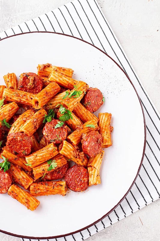 Rigatoni pasta with spicy sausage, and rich tomato sauce served, on a white plate, homemade