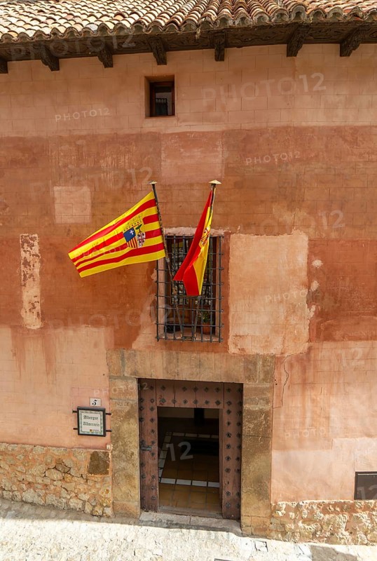 Alberque hostel building with flags flying, historic buildings in medieval village of AlbarracÃ­n, Teruel province, Aragon, Spain