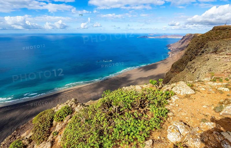 View from the Risco de Famara cliffs to the coast and the sea with the Famara beach, Playa de Famara, Lanzarote, Canary Islands, Spain