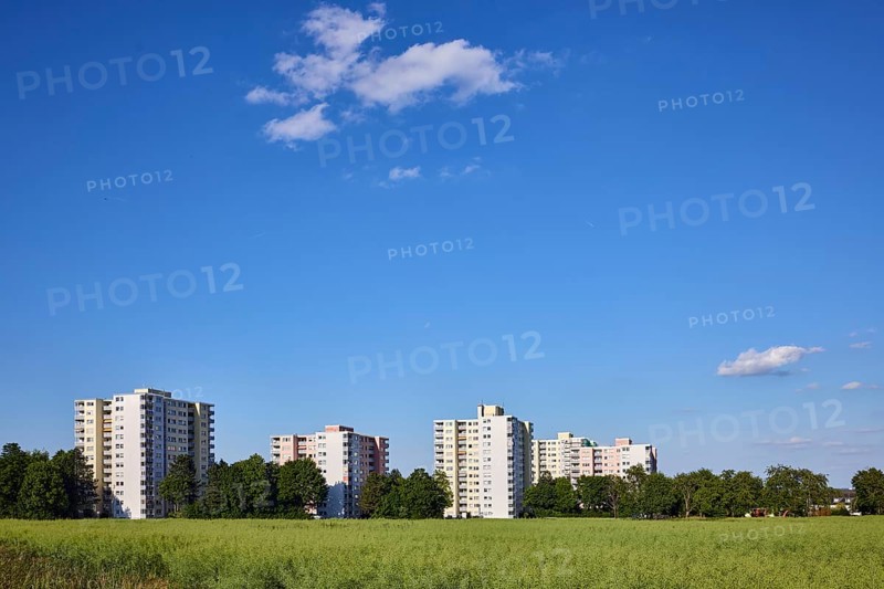 View of skyscrapers on NiederhöchstÃ¤dter StraÃŸe, residential buildings, trees, cultivated landscape, field, oilseed rape (Brassica napus), blue sky, cumulus clouds, Steinbach, Taunus, Hochtaunus, Hesse, Germany