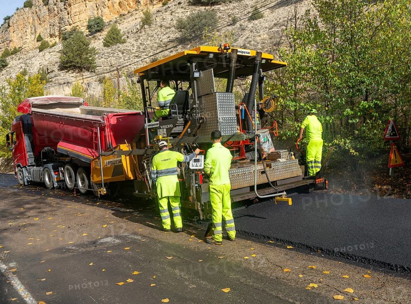 Asphalt road construction team of workers resurfacing tarmac in rural area, near Albarracin, Teruel province, Aragon, Spain