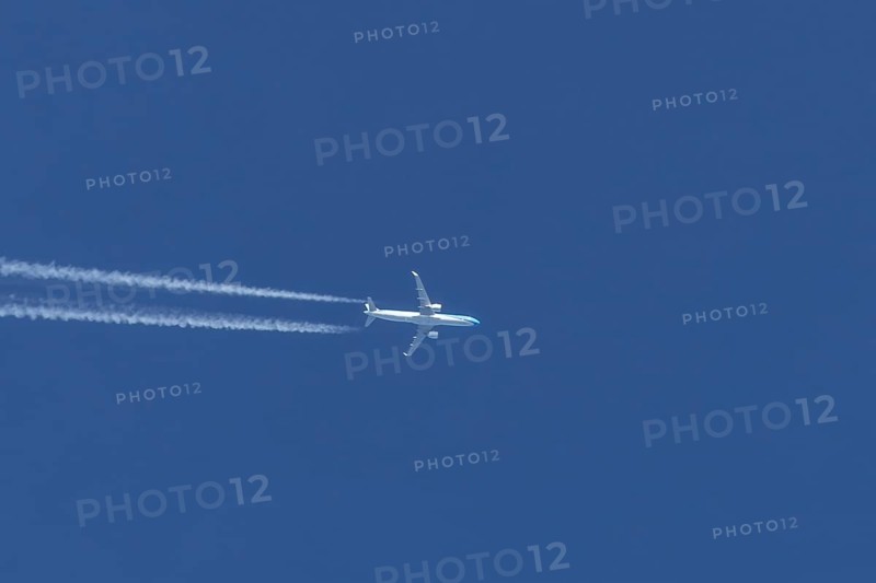 Jet passenger aircraft flying in a blue sky with contrails or vapour trails behind, England, United Kingdom