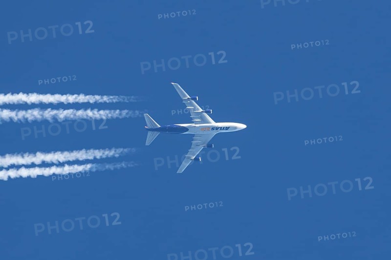 Boeing 747 jumbo jet cargo aircraft of Atlas air airlines flying in a blue sky with contrails or vapour trails behind, England, United Kingdom