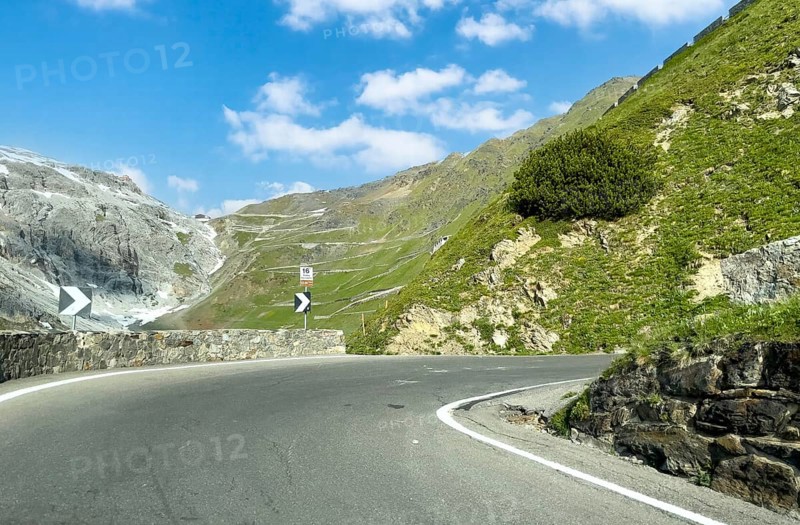 View of the hairpin bend in front with signpost 16th hairpin bend Tornante 2320 metres narrow, hidden bend from the eastern ramp Ascent to the descent from the Stelvio Stelvio Alpine Pass mountain road above the tree line, with many hairpin bends in the background leading to the pass summit of 2757 2758 metres high pass road mountain pass Stelvio Stelvio Pass, Stelvio, South Tyrol, Alto Adige, Italy