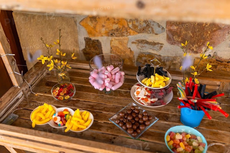 Delicious assortment of colorful candies presented on wooden table at a wedding reception, creating a vibrant and tempting candy bar