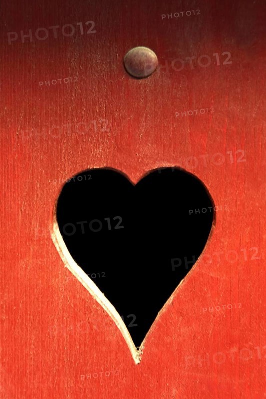 A heart-shaped cutout in a red wooden surface adds a whimsical touch. The contrasting dark interior evokes feelings of love and warmth
